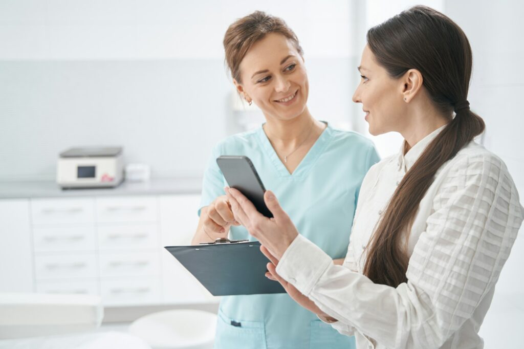 Woman using cellphone and talking with doctor in beauty salon