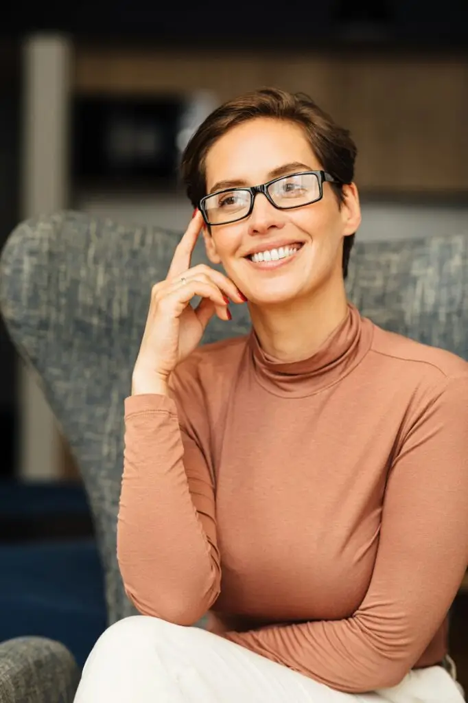 Beautiful smiling woman in eyeglasses relaxing in an armchair