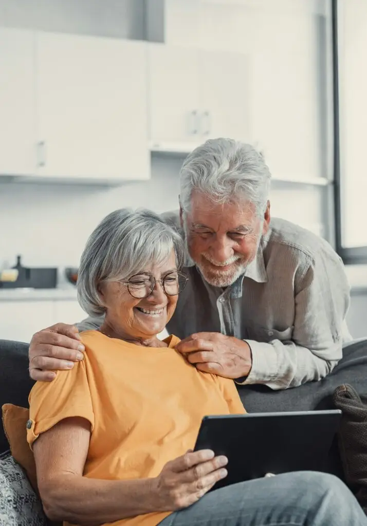 Happy older couple using computer tablet together at home, excited mature ma